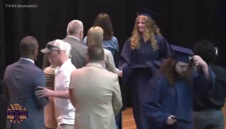 An unnamed father of a graduate pictured shoving Superintendent Rainey Briggs (far left) off the stage. In 2018, the same high school made national news after a photo emerged of several students performing the Nazi salute